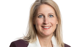 Person mit blondem Haar und Bluse in einem Portrait 