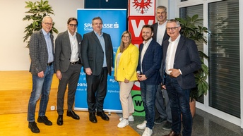 Sieben Personen stehen nebeneinander in einem Veranstaltungsraum der WK-Bezirksstelle Schwaz und blicken in die Kamera. Hinter ihnen sind ein Banner der Sparkasse Schwaz sowie ein WKO-Aufsteller zu sehen.