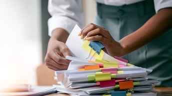 Eine Person sortiert einen Stapel an Unterlagen