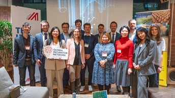 Gruppenfoto von mehreren Personen in Bürokleidung vor einer Leinwand, auf der die Karte Europas projiziert ist. Eine der Personen hält ein Schild, auf dem global incubator network steht