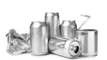 Vier stehende Aludosen, eine liegende Aludose und eine zerknüllte Aluverpackung auf weißem Unter- und Hintergrund