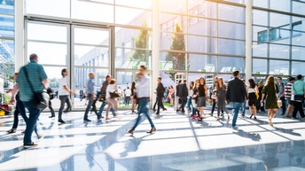 Personen gehen durch eine helle Eingangshalle aus Glas