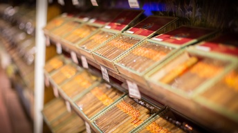 Seitliche Nahaufnahme vieler, verschiedener Zigarren in Regalen mit Preisschildern darunter