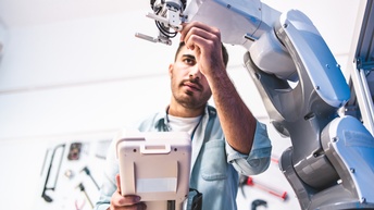 Person arbeitetet an einem Roboterarm in einem technischen Labor