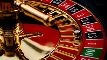 Nahaufnahme eines goldenen Roulette-Rades mit einer Kugel, die im schwarzen Feld 13 liegt