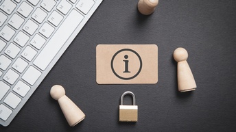 Karte mit Informationssymbol, Holzfiguren, Schloss und Tastatur auf einem dunklen Untergrund, Topshot