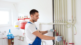 Person arbeitet an einem Heizsystem in einem Gebäude