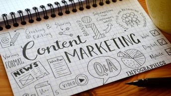 Karierter Notizblock mit Scribbles zu Content Marketing