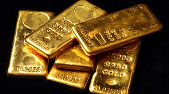 Sechs neben- und aufeinander platzierte Goldbarren mit eingestanzten Registrierungsnummern und 1000 Gramm bzw. ein Kilogramm 9950 Gold auf schwarzem Hintergrund