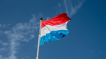 Die Flagge Luxemburgs weht unter blauem Himmel im Wind.