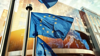 EU-Flagge in Wind wehen, im Hintergrund Glasfront eines Gebäudes