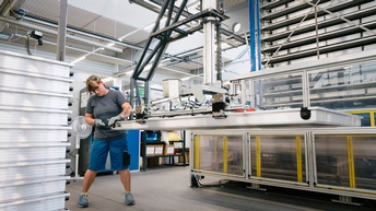 Person steht in Industriestätte und bearbeitet Solarpaneel