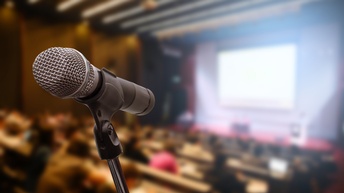 Nahaufnahme eines Mikrofons vor einem Publikum in der Unschärfe