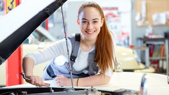 Lächelnde Person über offene Motorhaube gebeugt