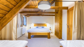 Blick auf ein Schlafzimmer mit Betten aus Holz und Holzverkleidung der Dachschrägen