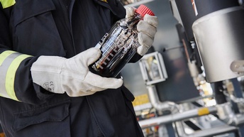 Eine Person hält eine Flasche mit Rohöl in den Händen