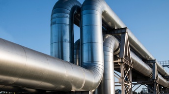 Zwei große Pipelines verlaufen parallel nebeneinander vor blauem Himmel