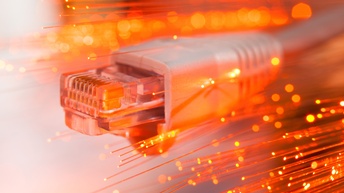 Detailansicht eines Datenkabels umgeben von orangerot leuchtenden Glasfasern 