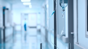 In einem Flur eines Krankenhauses hängt eine Infusionsflasche kopfüber