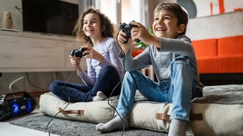 Zwei Kinder spielen ein Computerspiel und halten Spielekonsolen in ihren Händen