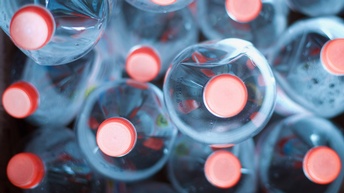 Detailansicht liegend aufeinandergestapelter blauer Plastikflaschen mit roten Schraubverschlüssen