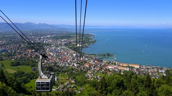 Seilbahn über Stadt und Bodensee mit Blick auf Ufer und Berglandschaft