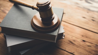 Richterhammer liegt auf mehreren Büchern auf hölzernen Untergrund