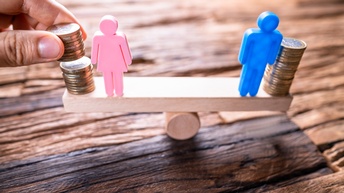 Eine Holzwippe im leichten Schiefstand: Auf beiden Kanten stehen Spielfiguren auf Münzen, die rechte Figur steht auf mehr Münzen und kippt daher leicht zur Seite. Bei der anderen Figur platziert eine Hand weitere Münzen.