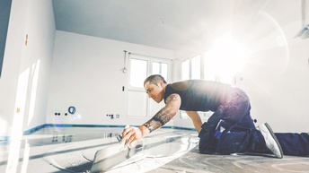 Person am Boden kniend beim Verstreichen von Zementmörtel