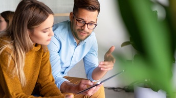 Zwei Personen über Tablet gebeugt