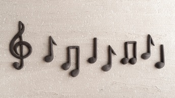 Ein Notenschlüssel und verschiedene Noten auf hellem Hintergrund. Die Symbole sind aus einem festeren Material wie Plastelin oder Knetmasse