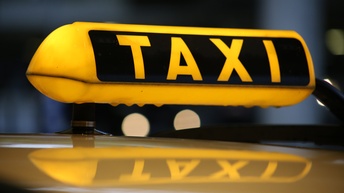 Ein gelb leuchtendes Taxischild auf einem Fahrzeug bei Nacht