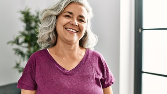 Porträt einer lächelnden Person mit grauen welligen Haaren