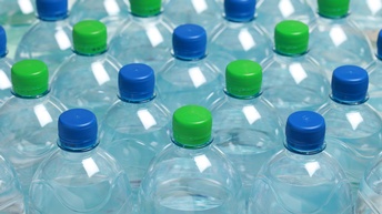 Mehrere Plastikflaschen mit Wasser und blauen und grünen Verschlüssen in Vogelperspektive