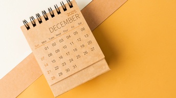 Aufnahme eines Kalenderblattes aus der Vogelperspektive. Das Kalenderblatt zeigt den Dezember 2025
