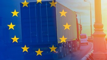 Rückseite eines LKWs, der einen Container geladen hat. Der LKW fährt auf einer Straße hinter einem PKW. Das Bild ist überlagert von einer transparenten EU-Flagge.