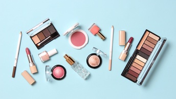 Make-up Kassetten, Nagellacke, Lippenstifte und Rouge Dosen auf einem hellblauen Untergrund, Vogelperspektive