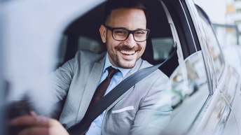 Lächelnde Person mit Brillen blickt aus Auto