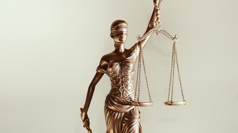 Justitia Figur hält mit verbundenen Augen eine Waagschale in der einen Hand und in der anderen ein Schwert, Symbolik des Rechts