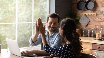Junges Paar sitzt am Küchentisch vor einem Laptop