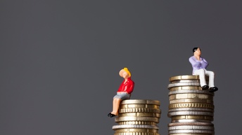 Zwei Figuren sitzen auf unterschiedlich hohen Münzstapeln.