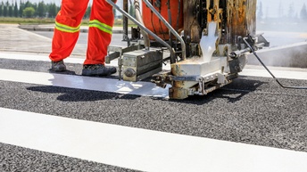 Detailansicht einer Maschine, die von Person geschoben wird, die Farbe auf Straße für Markierungen appliziert