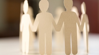 Girlande aus hellem Papier ausgeschnittene Personen, die als kleine Papierfiguren einen geschlossenen Kreis und halten sich dabei an den Händen halten