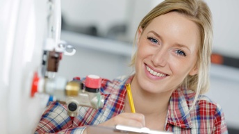 Eien junge Installateurin beim Warten eines Boilers