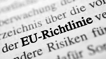 Schriftzug in schwarz auf weißem Papier EU-Richtlinie, umgebender Text unscharf