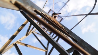 Ansicht von unten eines Metallmastens, oben verschwommen Person unter wolkenverhangenem Himmel erkennbar