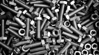 Nahaufnahme sehr vieler länglicher, dunkelgrauer Schrauben, an deren einem Ende eine Mutter jeweils steckt