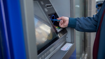 Nahaufnahme von einer Hand, die eine EC-Karte in einen Bankomat einführt