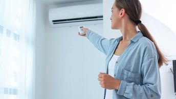 Eine Person bedient per Fernbedienung eine Klimaanlage in einem Zimmer