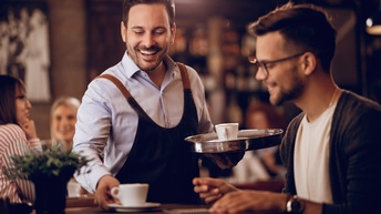 Person in einem Kaffeehaus wird ein Kaffee serviert 